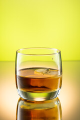 whiskey with ice splash in a glass on a colored gradient background