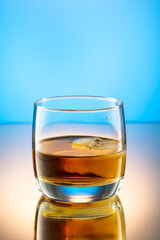 whiskey with ice splash in a glass on a colored gradient background