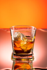 whiskey with ice splash in a glass on a colored gradient background