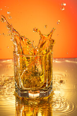 whiskey with ice splash in a glass on a colored gradient background
