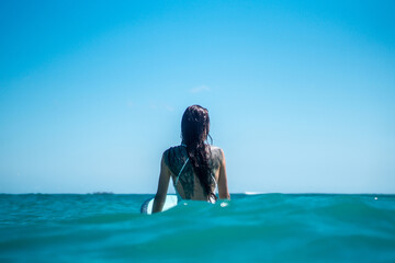 Portrait of surfer girl with tattoo on surf board in blue ocean