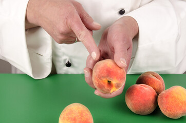 female chef shows with her index finger on a peach