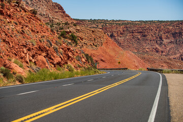 Landscape with orange rocks, sky with clouds and asphalt road in summer. American road trip.