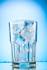 pour clear water into a glass with chunks of pure real ice on a blue gradient background