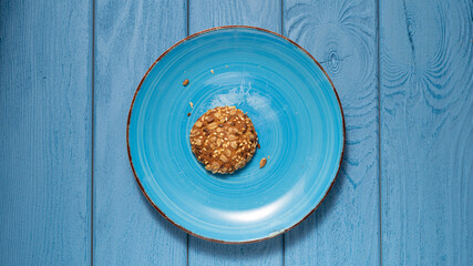 TOP VIEW: Last oatmeal cookie on a blue plate on a blue table