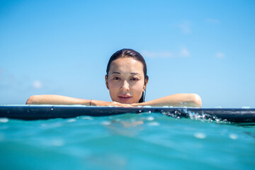 Portrait of surfer girl on surf board in blue ocean