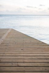 Fototapeta premium Timber deck platform with blue water ocean in the background and sky clouds