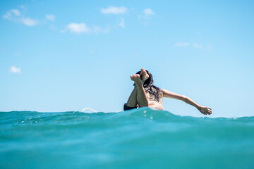 Portrait of surfer girl on surf board in blue ocean