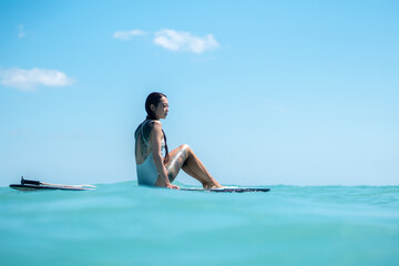 Portrait of surfer girl on surf board in blue ocean