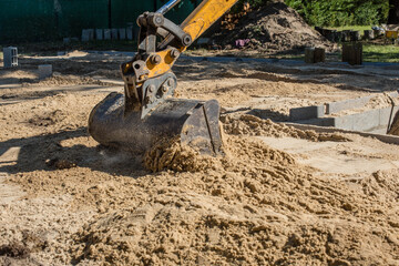 Fototapeta premium mechanical excavator in action on a construction site of a house