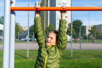 Front view Boy kid child 9s performing pull-ups outdoor exercise machines
