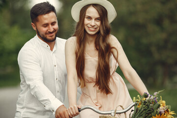 Couple in a summer park. People with vintage bicycle. Girl in a hat.