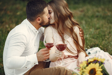 Couple in a field. Brunette in a white dress. Pair sitting on a grass.