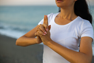 Yoga concept. Hands of female practicing yoga by seaside.