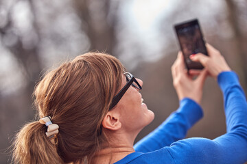 Young woman using smartphone in autumn colored park.