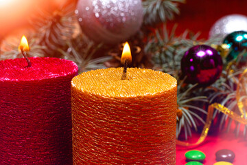 A beautiful Christmas image - a burning candle in gold color against the background of the Christmas tree. Romantic holiday photo with bokeh