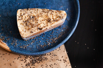 Cheesecake on a blue plate with scattered sesame seeds