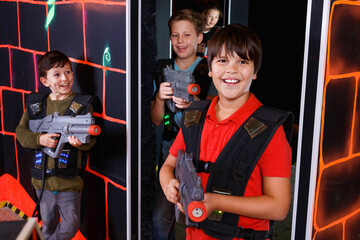 Fototapeta na wymiar Portrait of happy preteen boy with laser pistol posing in laser tag labyrinth