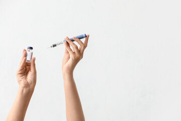 Female hands with bottle of insulin and syringe on light background. Diabetes concept