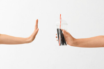 Female hands with plastic cup and cocktail straws showing stop gesture on light background. Ecology concept