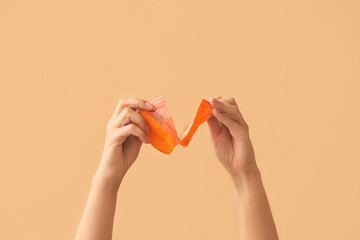 Female hands tearing plastic cup on color background. Ecology concept
