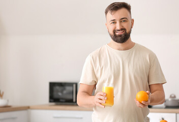 Fototapeta na wymiar Man with orange and juice in kitchen