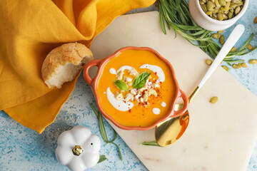 Tasty pumpkin cream soup in pot on color background