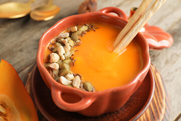 Tasty pumpkin cream soup in pot on table