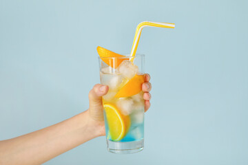 Female hand with cold cocktail in glass on color background