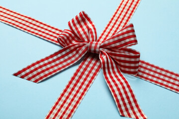 Checkered gift bow on blue background, close up
