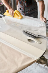 The mechanic works with a grinding tool. Sanding of car elements. Garage painting car service. Repairing car section after the accident.