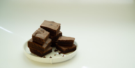 Chocolate brownie sliced into square slices on a white plate.