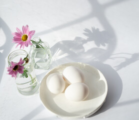 Obraz na płótnie Canvas Still life with eggs and delicate flowers on a sunny window