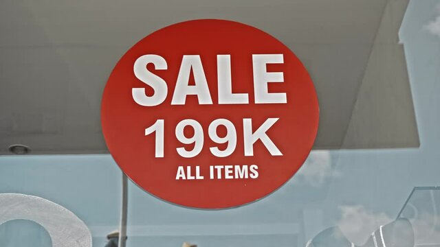 Red round sign hanging on a glass window with the inscription Sale 199 K all items