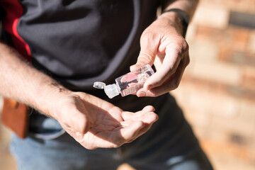 senior man aged hands applying sanitzer remove germs bugs coronavirus keeping clean percaution dispense small travel sized bottle container 