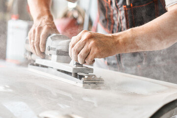 The mechanic works with a grinding tool. Sanding of car elements. Garage painting car service. Repairing car section after the accident.