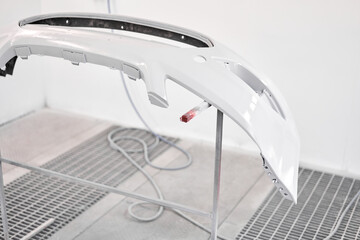 Bumper of the car section in the paint chamber, is covered with primer. Garage painting car service. Repairing car body work after the accident by working sanding primer before painting.