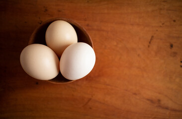 Three fresh white eggs in a wooden cup on a wooden table
木製テーブルの上にある木のカップに入った３つの白い卵 4
