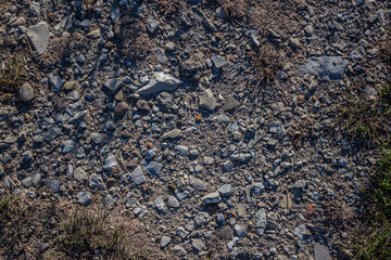 Texture of a pebble country road overgrown with grass