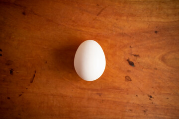 A fresh white egg on the center of a wooden table
木製テーブルの中央にある1つの新鮮な白い卵