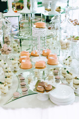 Wedding candy bar with different colored bright cupcakes, macaroons, cakes, jelly and fruits.