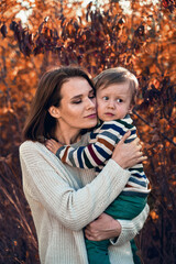 Cute little boy in his mother's arms. Woman at home carrying her newborn son.