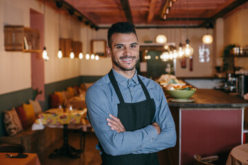 Cheerful positive handsome restaurant owner with crossed arms proud by himself looking at camera....