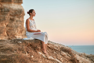 Dreamy woman write thoughts in notebook. Pensive mood and fresh air. Keeping diary and time alone...