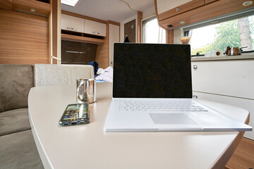 Homeoffice Arbeiten im Wohnwagen Wohnmobil mit Laptop und Internet im Urlaub unterwegs auf dem Campinglatz 