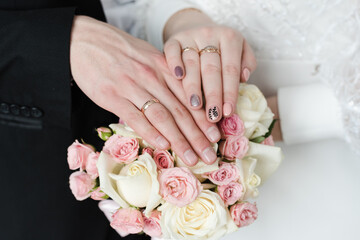 hands with wedding rings, wedding rings, bridal bouquet of pink roses
