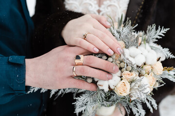hands with wedding rings, winter bridal bouquet, bride and groom