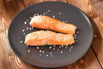 Fried salmon fillet with salt on the black plate.