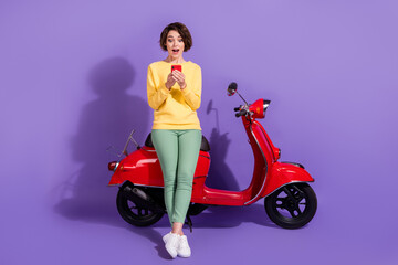 Fototapeta na wymiar Full length body size view nice attractive amazed cheerful girl sitting on bike using device browsing news post app 5g isolated over bright vivid shine vibrant lilac violet purple color background