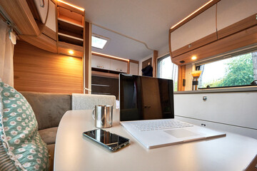 Homeoffice Arbeiten im Wohnwagen Wohnmobil mit Laptop und Internet im Urlaub auf dem Campinglatz 